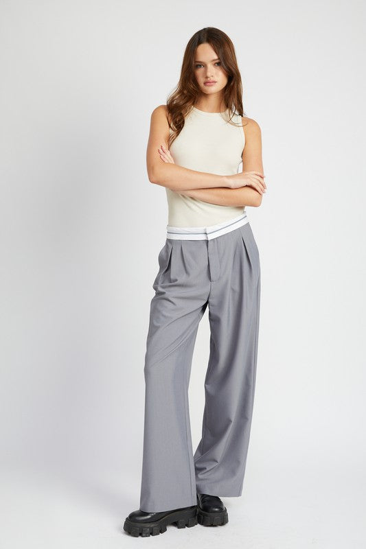 Woman wearing Emory Park Reverse Waist Band Tailored Pants in gray with white waistband and black shoes