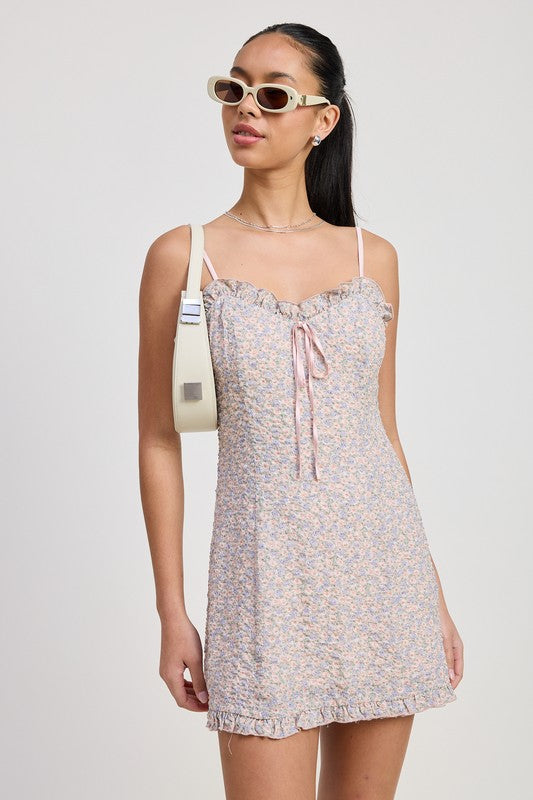 Emory Park Ruffle Mini Floral Dress with spaghetti straps and front tie detail worn with white sunglasses and shoulder bag