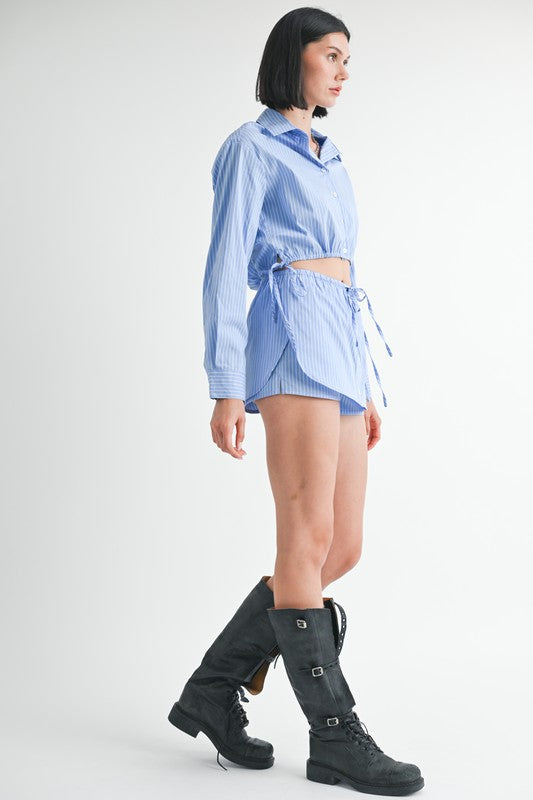 Model wearing Emory Park Drawstring Mini Skort With Buttons in blue stripe paired with oversized shirt and black buckle boots
