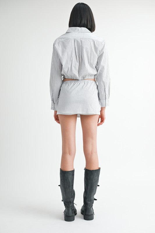Back view of model wearing Emory Park Drawstring Mini Skort With Buttons in striped fabric with knee high boots