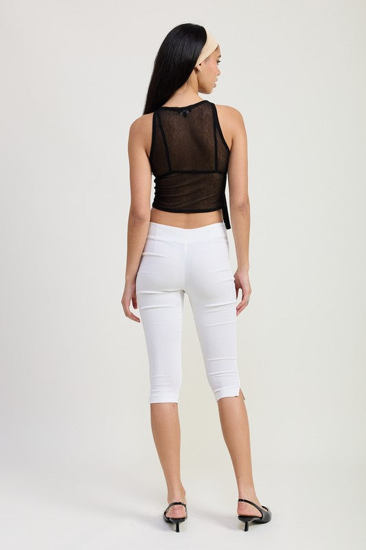 Back view of model wearing Emory Park Sleeveless Sheer Bow Top in black with white cropped pants