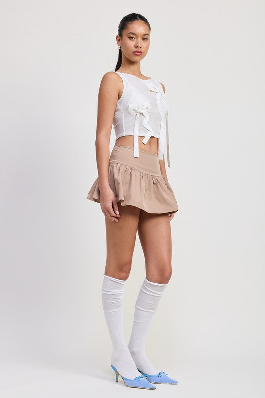 Emory Park sleeveless sheer bow top in white worn with beige mini skirt and blue heels