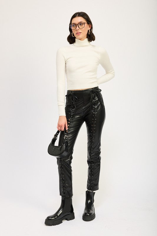 Emory Park model wearing Lace-Up Leather Trousers with white turtleneck, black boots and mini bag