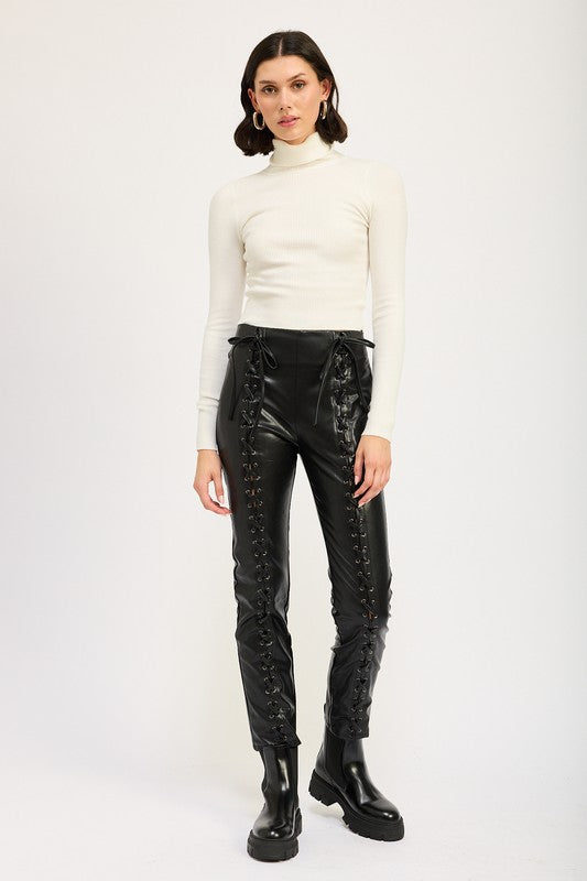 Model wearing Emory Park Lace-Up Leather Trousers in black high waist with front and side lacing paired with white turtleneck