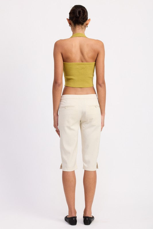 Back view of Emory Park Tailored Mid-Rise Bermuda Pants in cream on model wearing mustard halter crop top and black flats