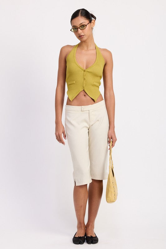 Model wearing Emory Park Tailored Mid-Rise Bermuda Pants in cream with green halter top and yellow bag