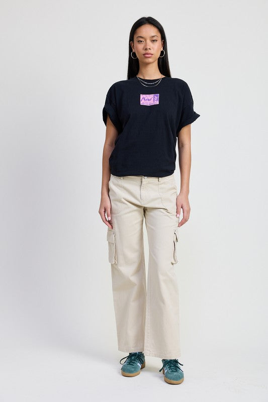 Emory Park model wearing beige Pocket Cargo Pants with side flap pockets and black logo tee