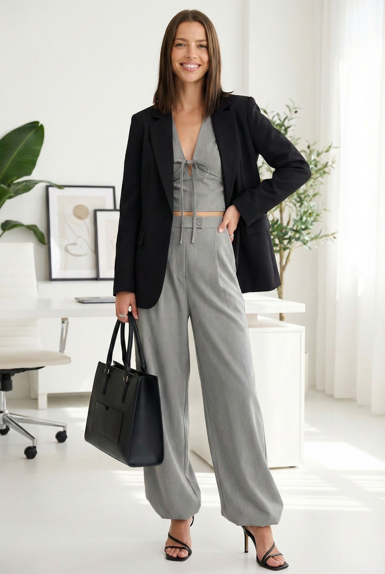 Model wearing Emory Park V-Neck Cropped Blouse With Rhinestones in Grey, styled with high-waisted wide-leg trousers and blazers and strappy heels standing in luxury office