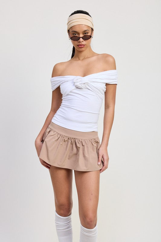 Emory Park white Off Shoulder Rosette Top with knot detail worn by model with beige skirt and sunglasses