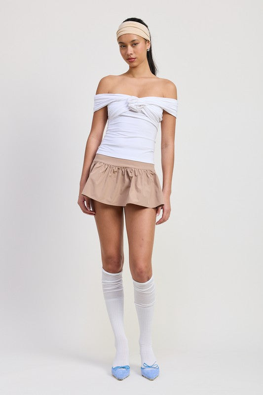 Model wearing Emory Park Off Shoulder Rosette Top in white paired with beige skirt and knee-high socks